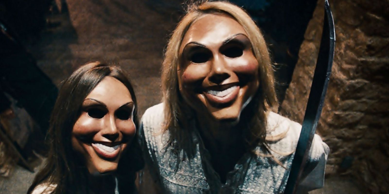 Two of the masked killers from The Purge, standing outside a house