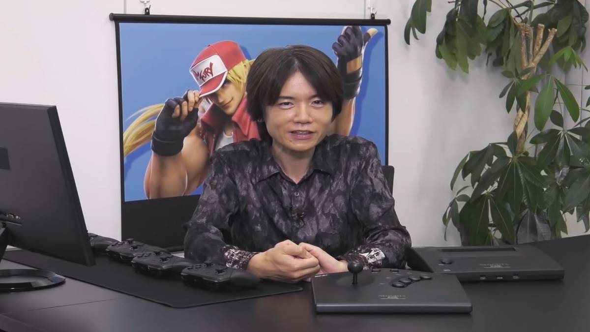 masahiro sakurai smiling in front of terry bogard poster