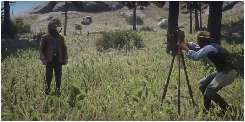 Albert Mason setting up his camera near Arthur in Red Dead Redemption 2