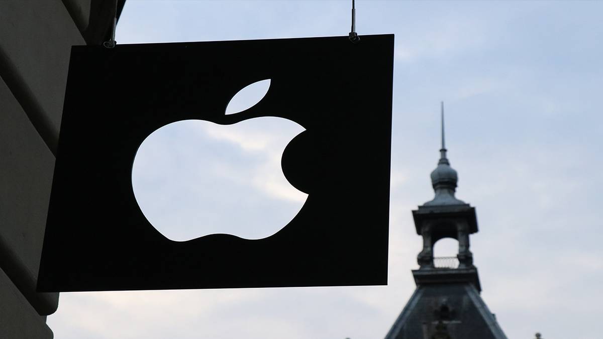 Apple logo in front of building at sunset