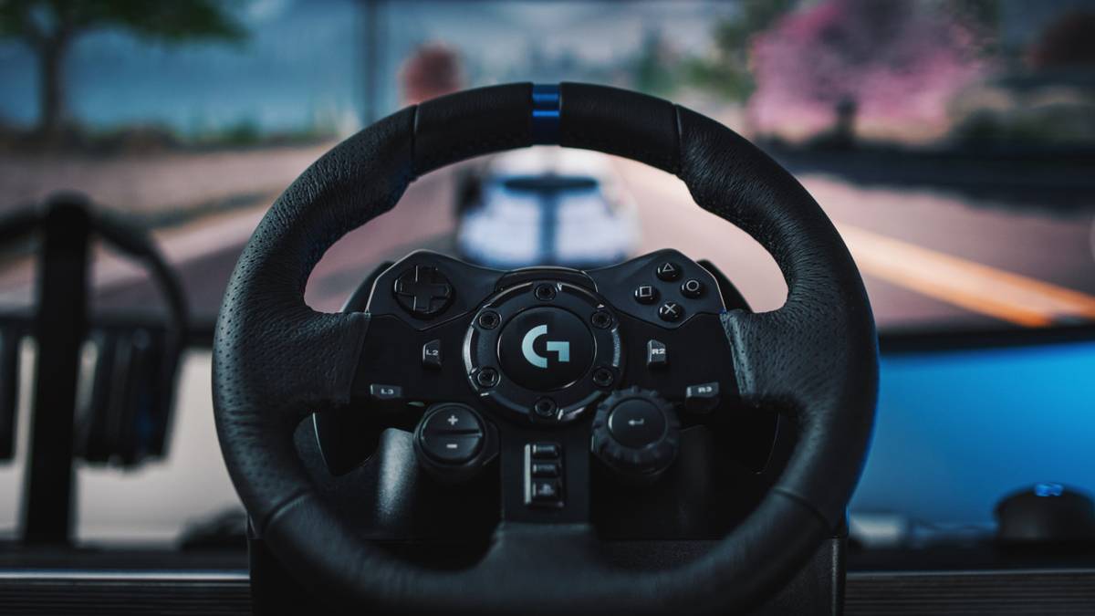 A Logitech G923 steering wheel sits in front of a computer screen playing a racing game.