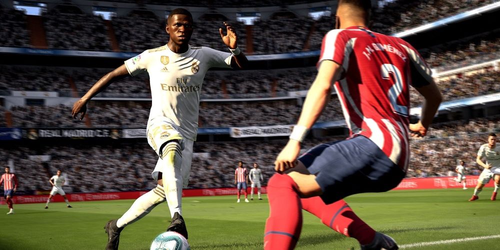 Fifa screenshot player in white uniform kicking a ball past a player in red and navy