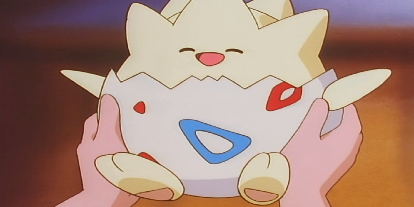 A happy Togepi in a trainer's arms