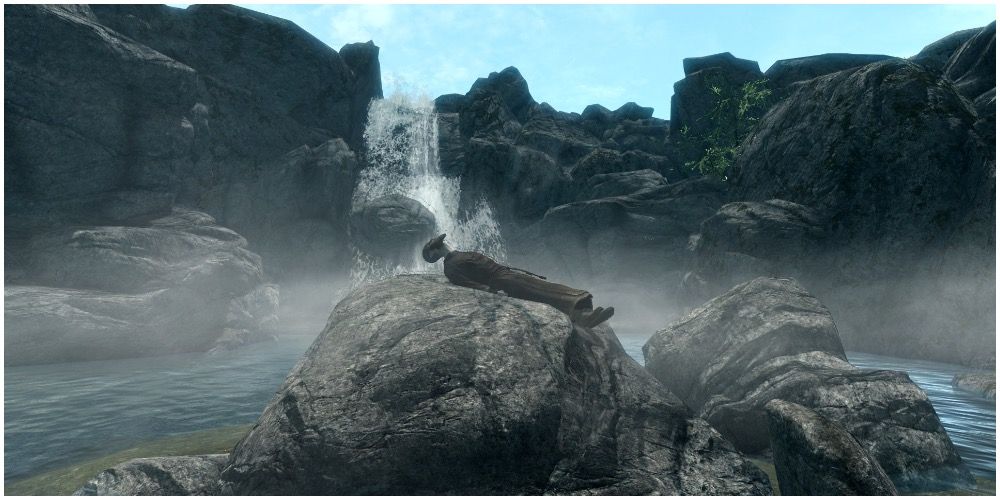 A dead alchemist on rocks near a waterfall