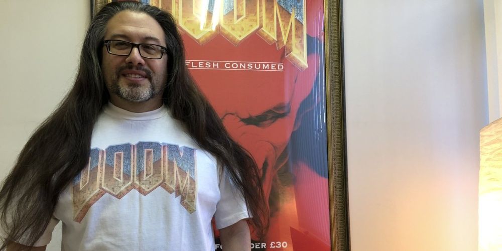 John Romero Doom Shirt In Front Of Doom Poster