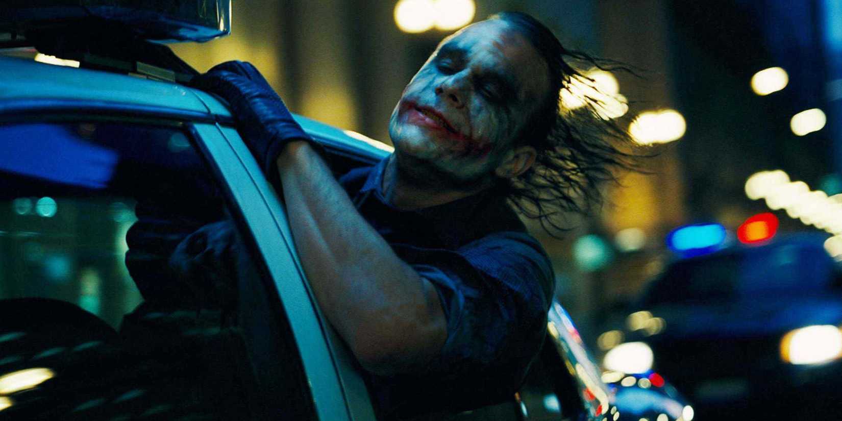 Heath Ledger as the Joker in The Dark Knight leans his head out of a car window