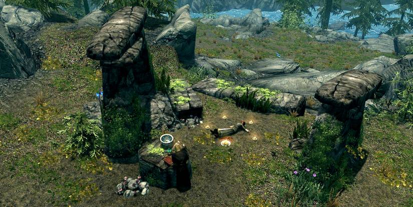 a necromancer preparing next to a dead body by some rocks