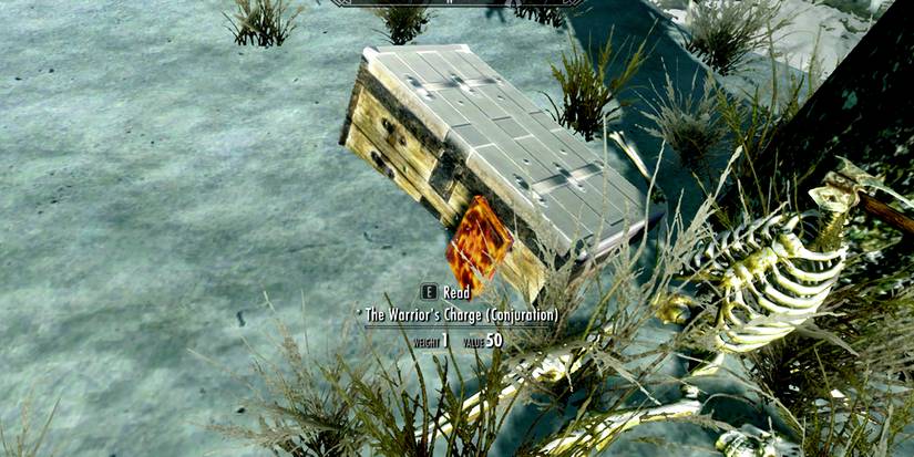 a chest next to a headless skeleton and a skill book in skyrim's snowy landscape.