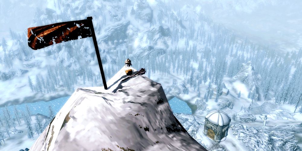 peak of a snowy mountain with a flag and some items overlooking skyrim