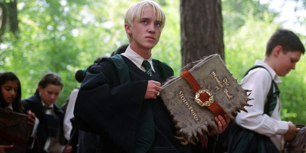 Draco Malfoy holding the Monster Book Of Monsters