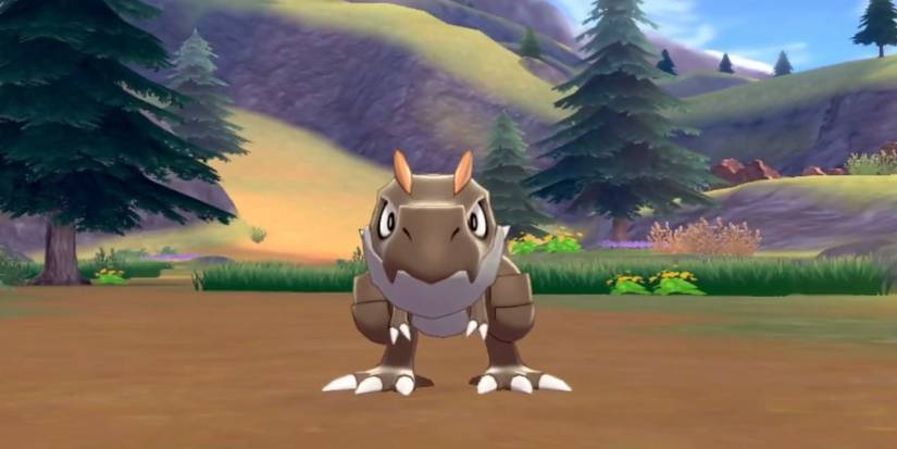 Tyrunt Pokemon in dirt field battle with mountains