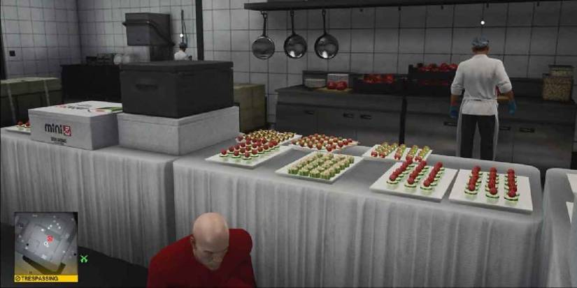 Hitman 3. Agent 47 crouching behind a table.