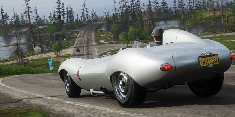Forza Horizon 4 Jaguar D-Type speeding down road towards forest