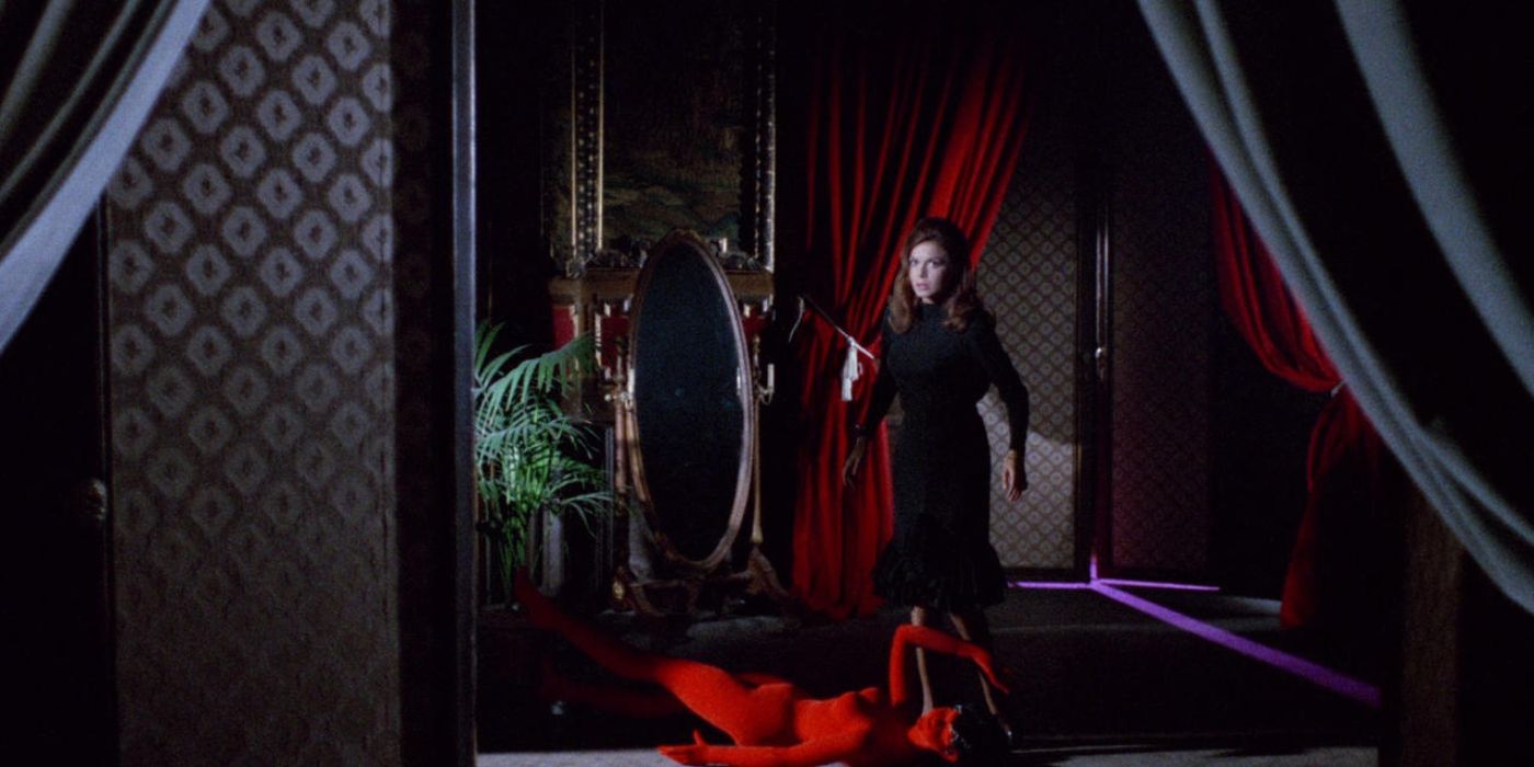 Кровь и черное кружево. Женщина в темной комнате с красными занавесками, стоящая над красным бархатным манекеном.