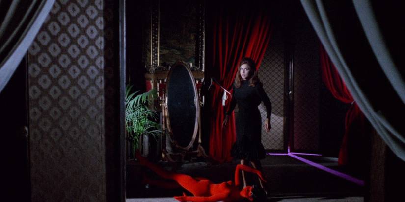 Blood And Black Lace still of woman in a dark room with red curtains caught standing over a red velvet mannequin