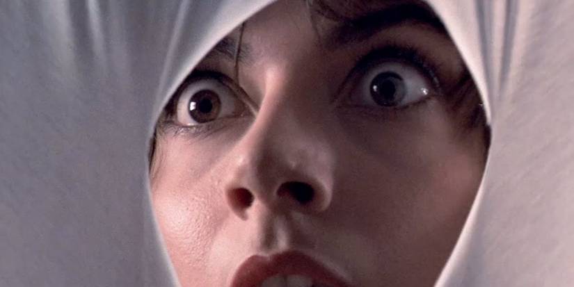 Tenebrae still of scared woman looking through hole in white sheet