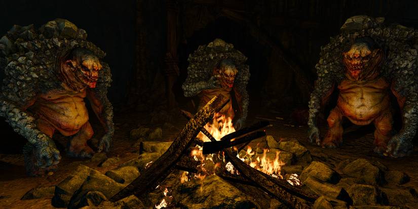 Cave Trolls are hunched around a bonfire