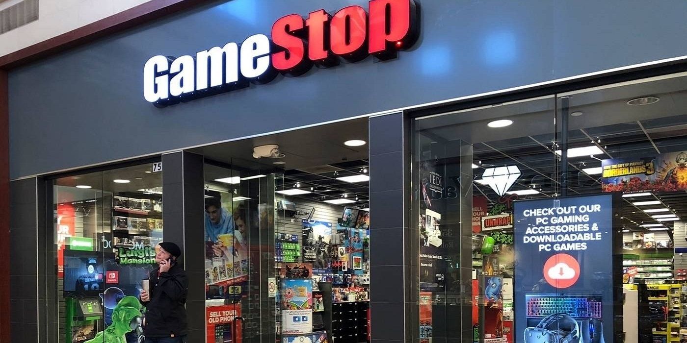 Exterior shot of a Gamestop store with a man stood outside on his phone