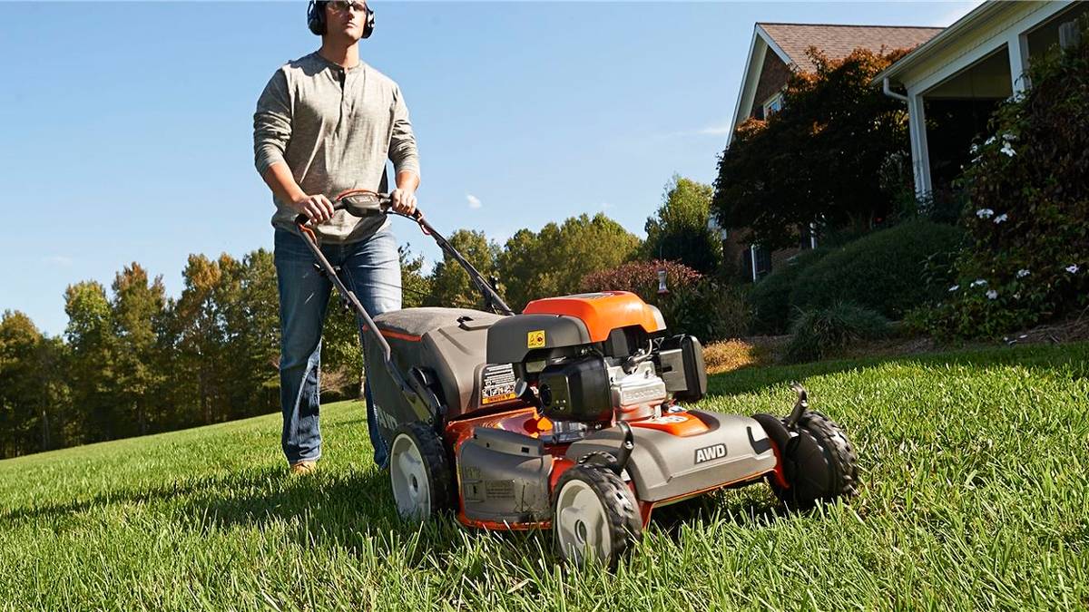 Photo of a man cutting some grass with a lawnmower.
