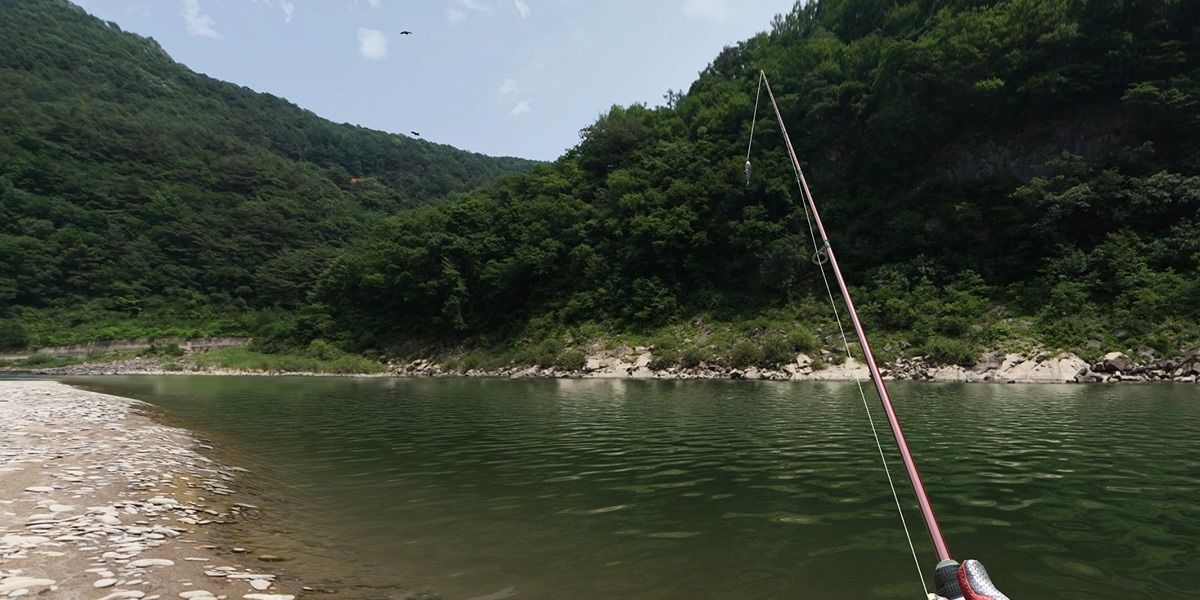 Fishing rod is seen in a bay area surrounded by mountain