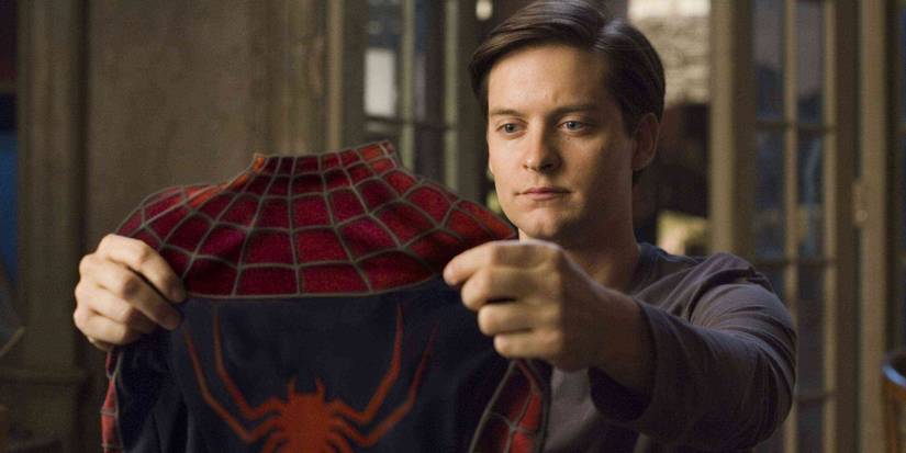 Tobey Maguire as Peter Parker holding the Spider-Man suit