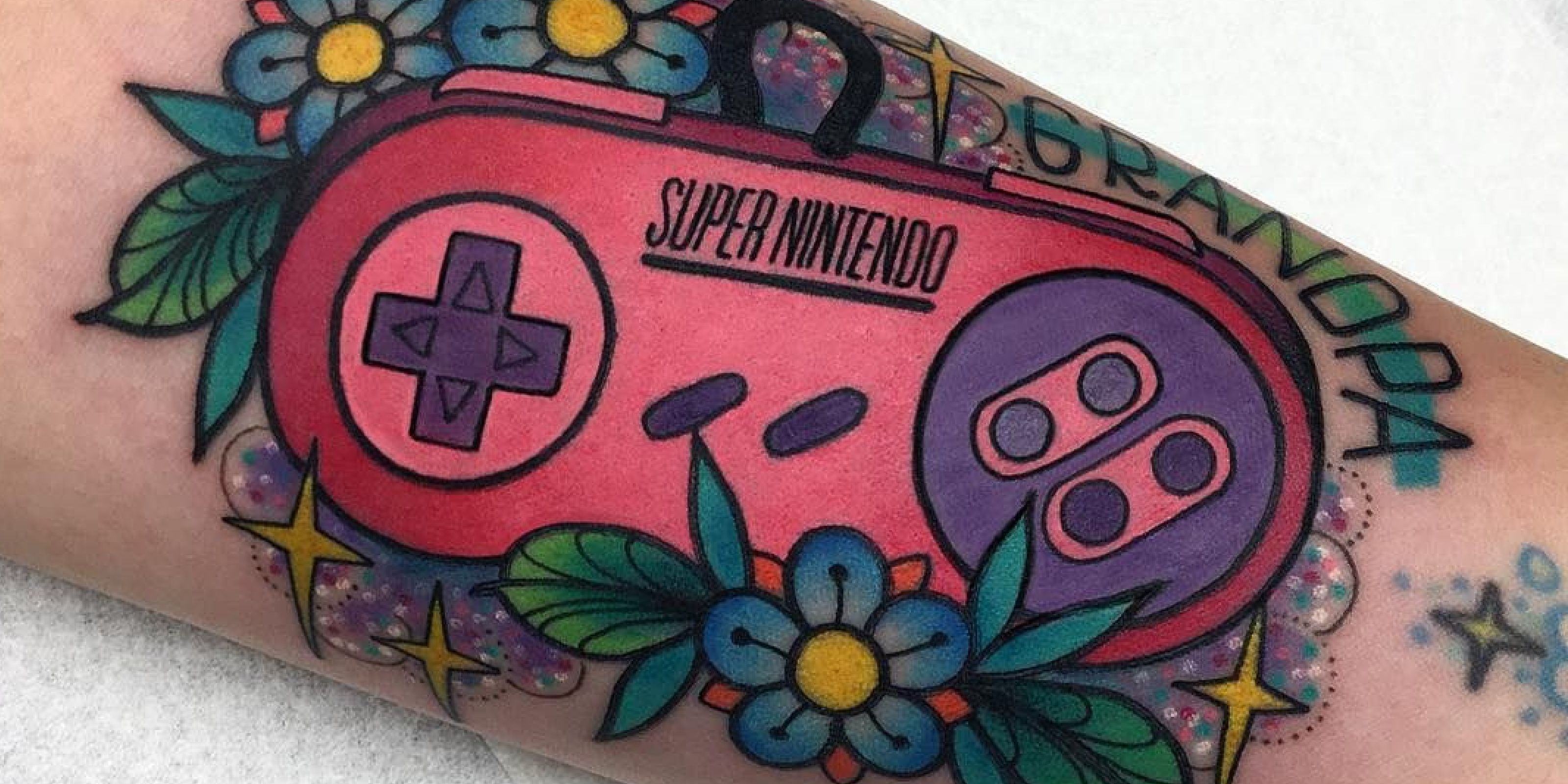 Pink Super Nintendo tattoo with blue flowers.