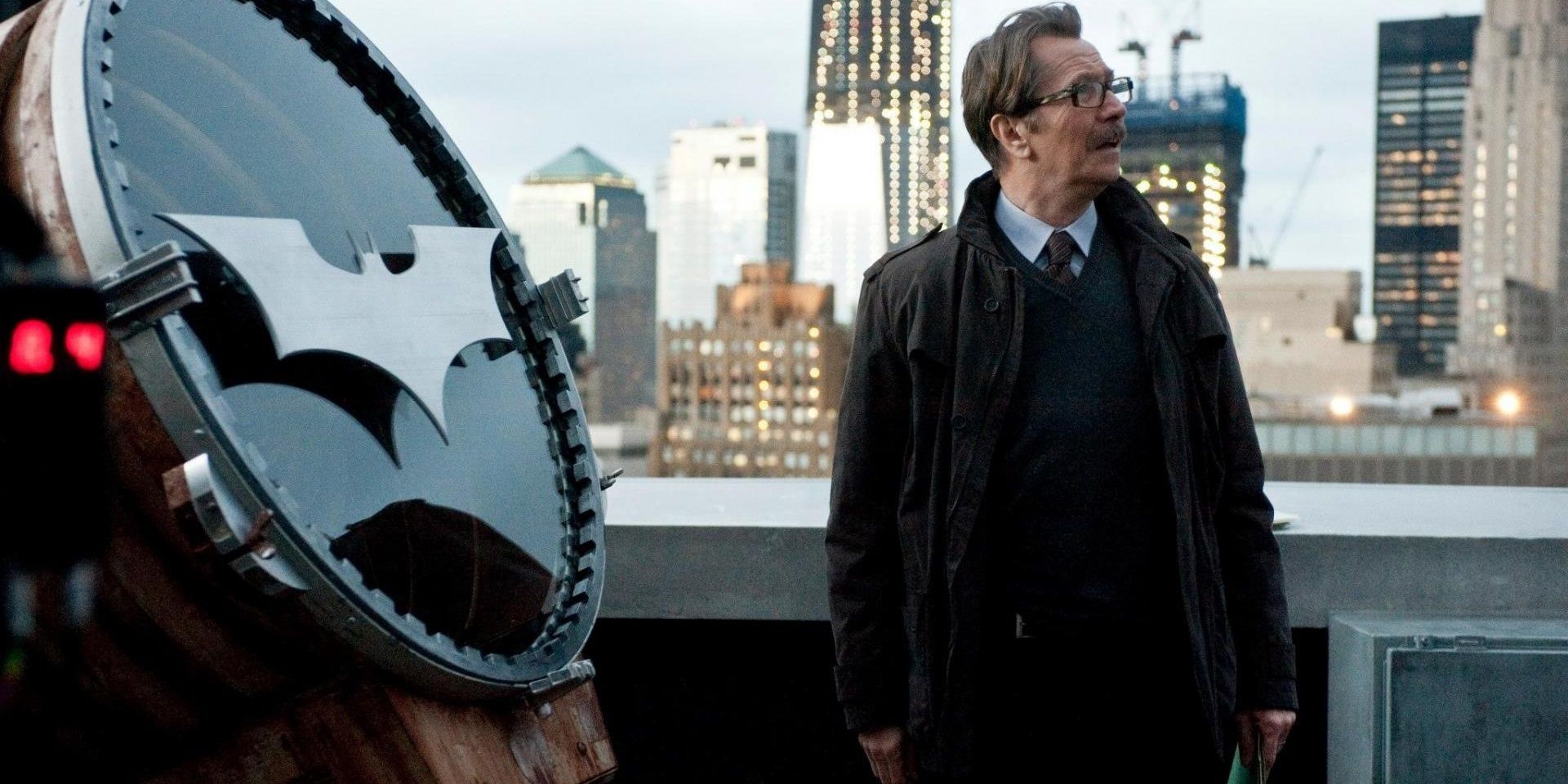 Gary Oldman as Commissioner Gordon standing next to the Bat-Signal