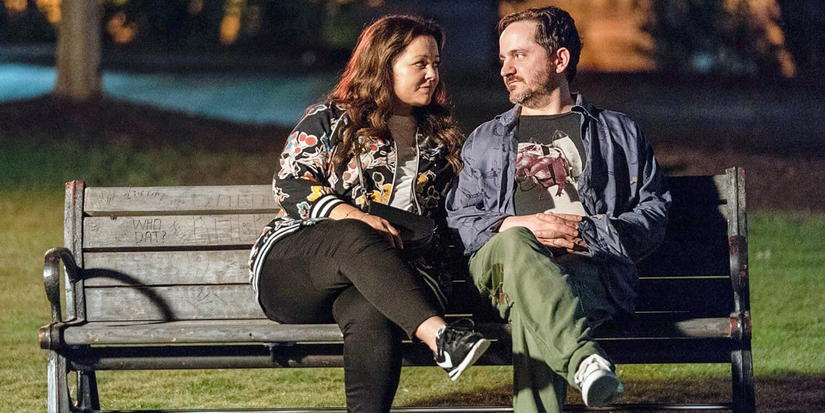 Melissa McCarthy and Ben Falcone on a bench in Superintelligence