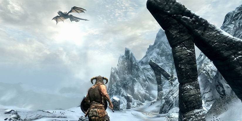 Skyrim screenshot showing a dragon flying above a snowy area.