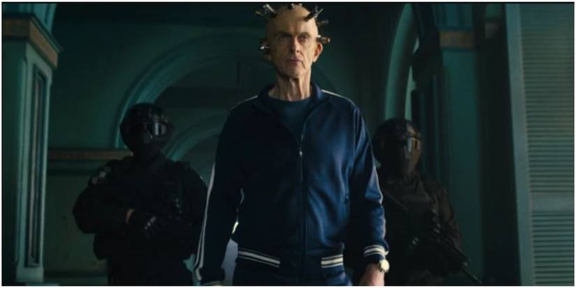 Thinker walking through building with guards behind him