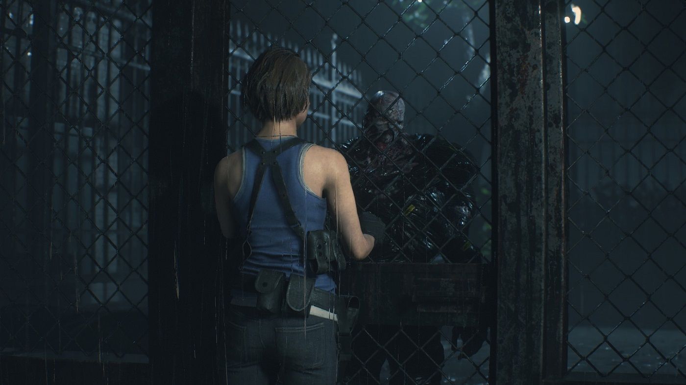 Screenshot from Resident Evil 2 Remake showing Claire on the opposite side of a chainlink fence to Nemesis.