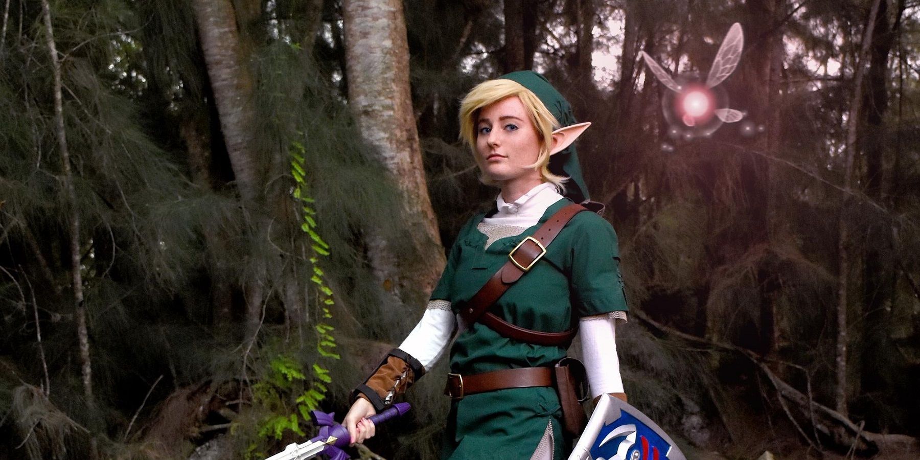A cosplay of Twilight Princess Link walking through a darkened forest.