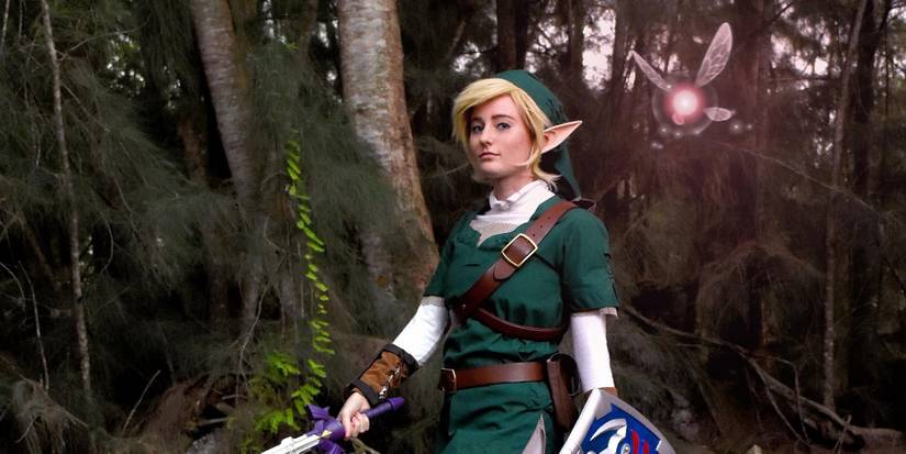 A cosplay of Twilight Princess Link walking through a darkened forest.