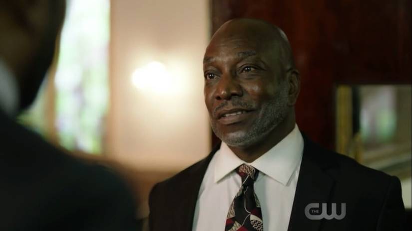 Jeremiah Holt in a suit converses with someone offscreen.