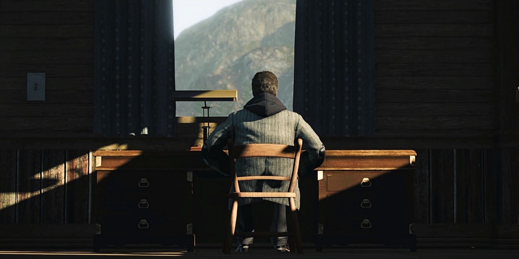 Screenshot from Alan Wake Remastered shwoing the titular character at a desk with his back to the camera.