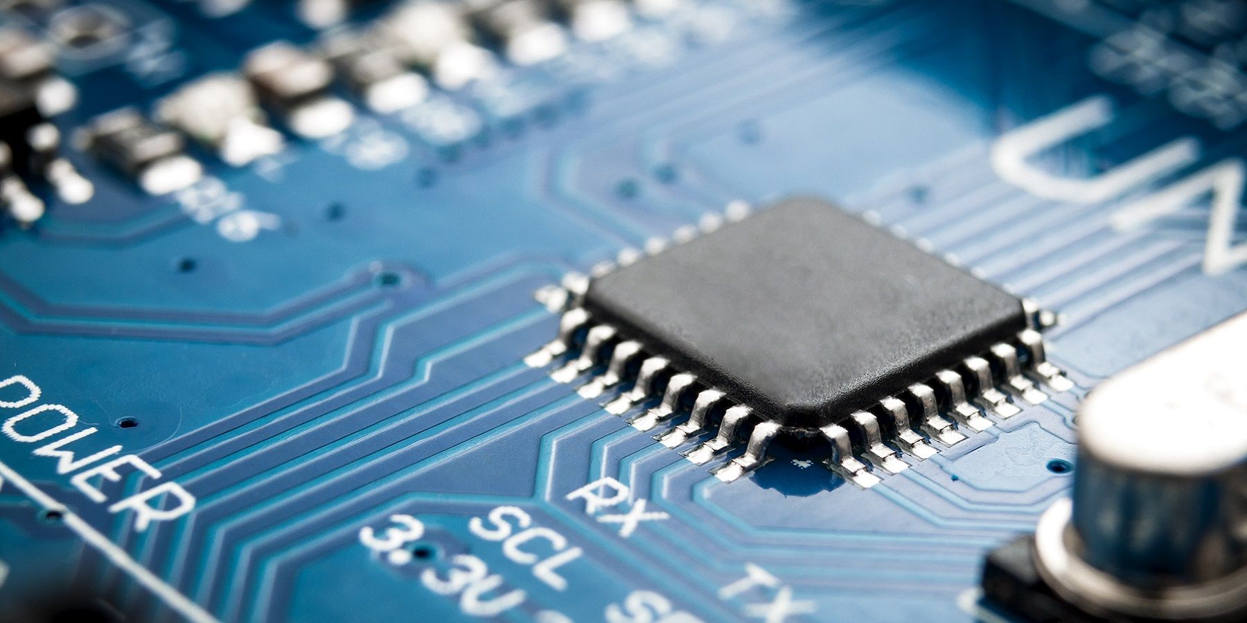 A photo showing a close up of a blue motherboard with a chip soldered to it.