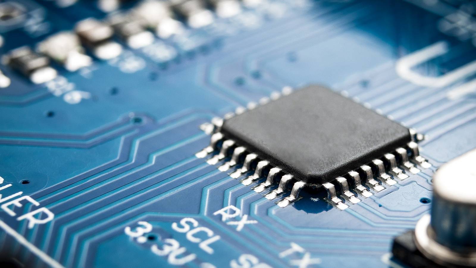 A photo showing a close up of a blue motherboard with a chip soldered to it.