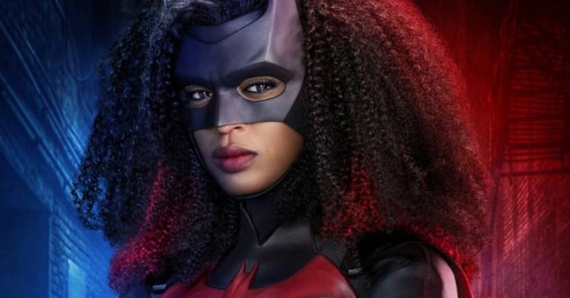 Ryan Wilder poses in the Batwoman costume against a blue and red background.