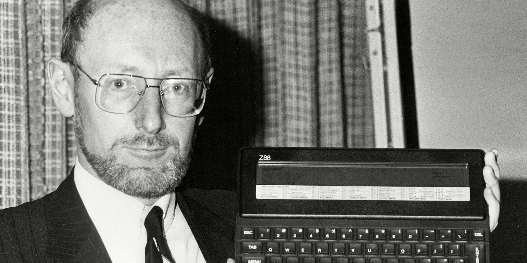 Black and white photo of Sir Clive Sinclair holding a Z88.