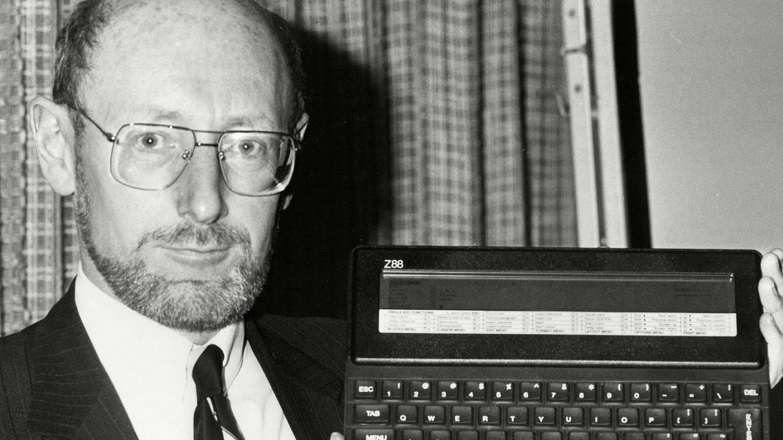 Black and white photo of Sir Clive Sinclair holding a Z88.