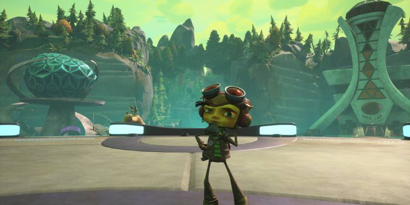 A boy in a leather cap with goggles on his forehead stands with his hand on his chin in front of two large, oddly shaped buildings