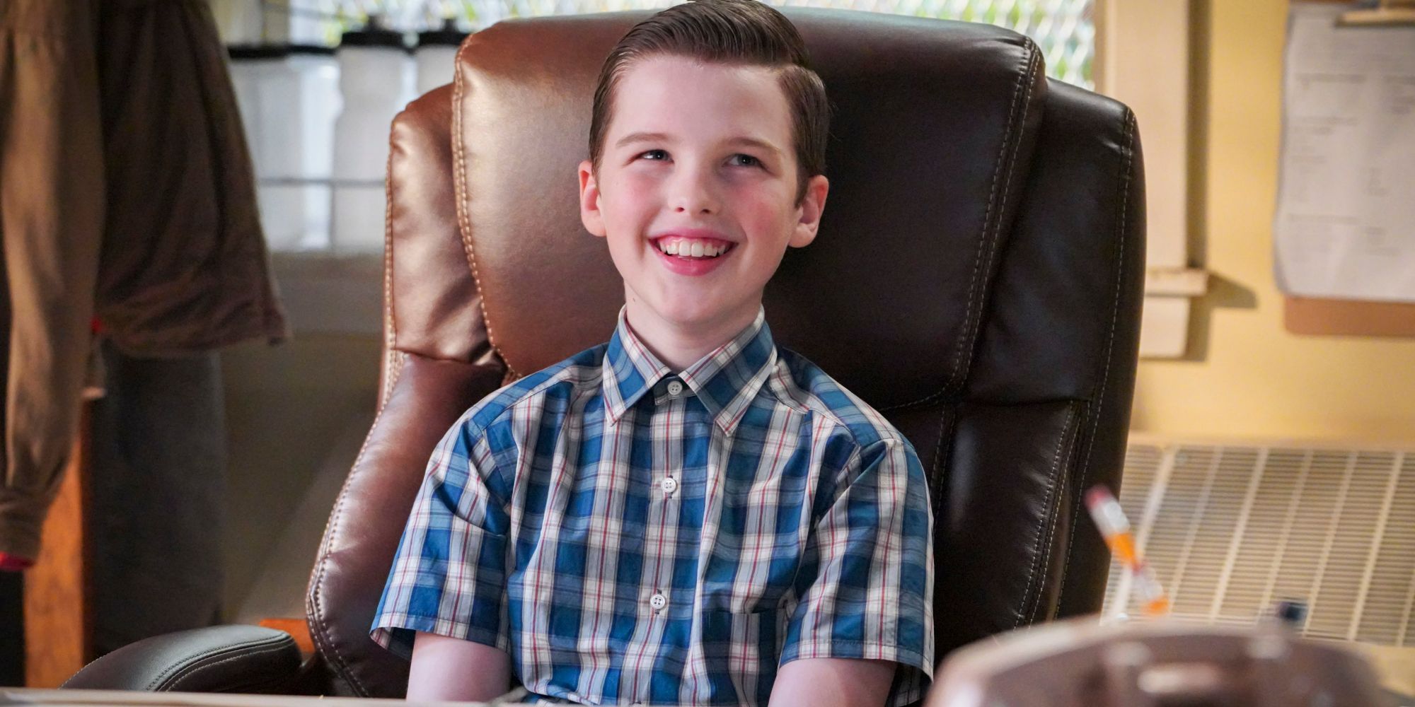 Young Sheldon sitting in a chair smiling in Young Sheldon