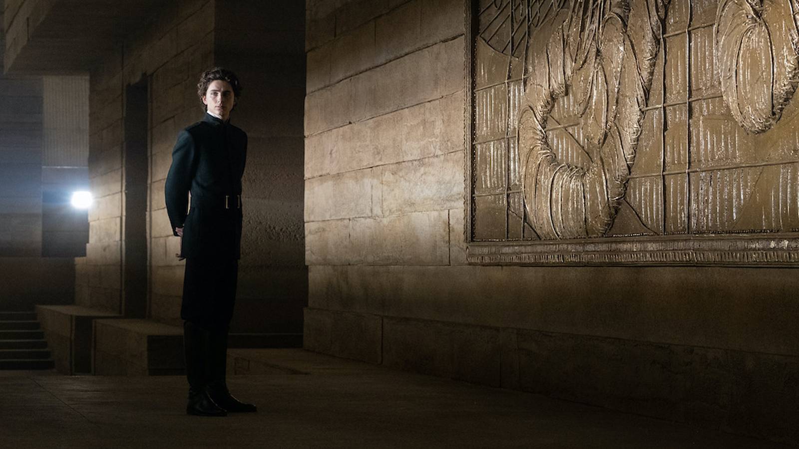 Paul stands before a massive relief carving on Arrakis in the 2021 fil-adaptation of Dune.