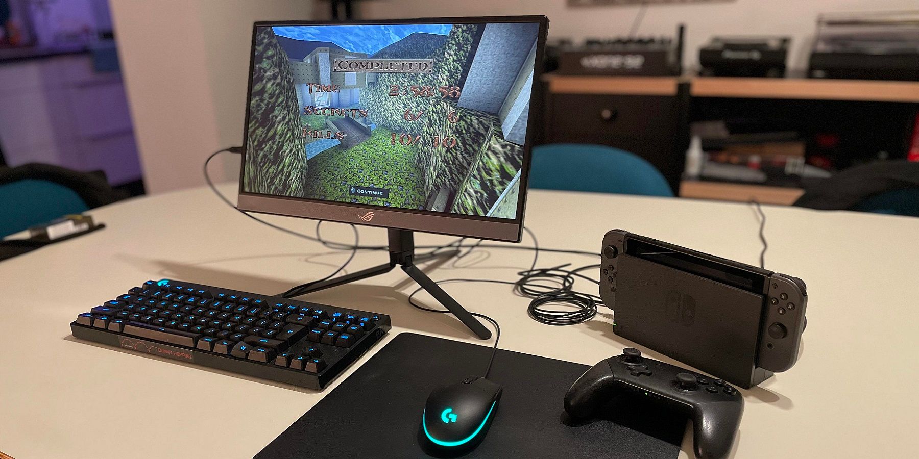 A photo of a Nintendo Switch hooked up to a mouse and keyboard, with a monitor showing a screenshot from Quake.