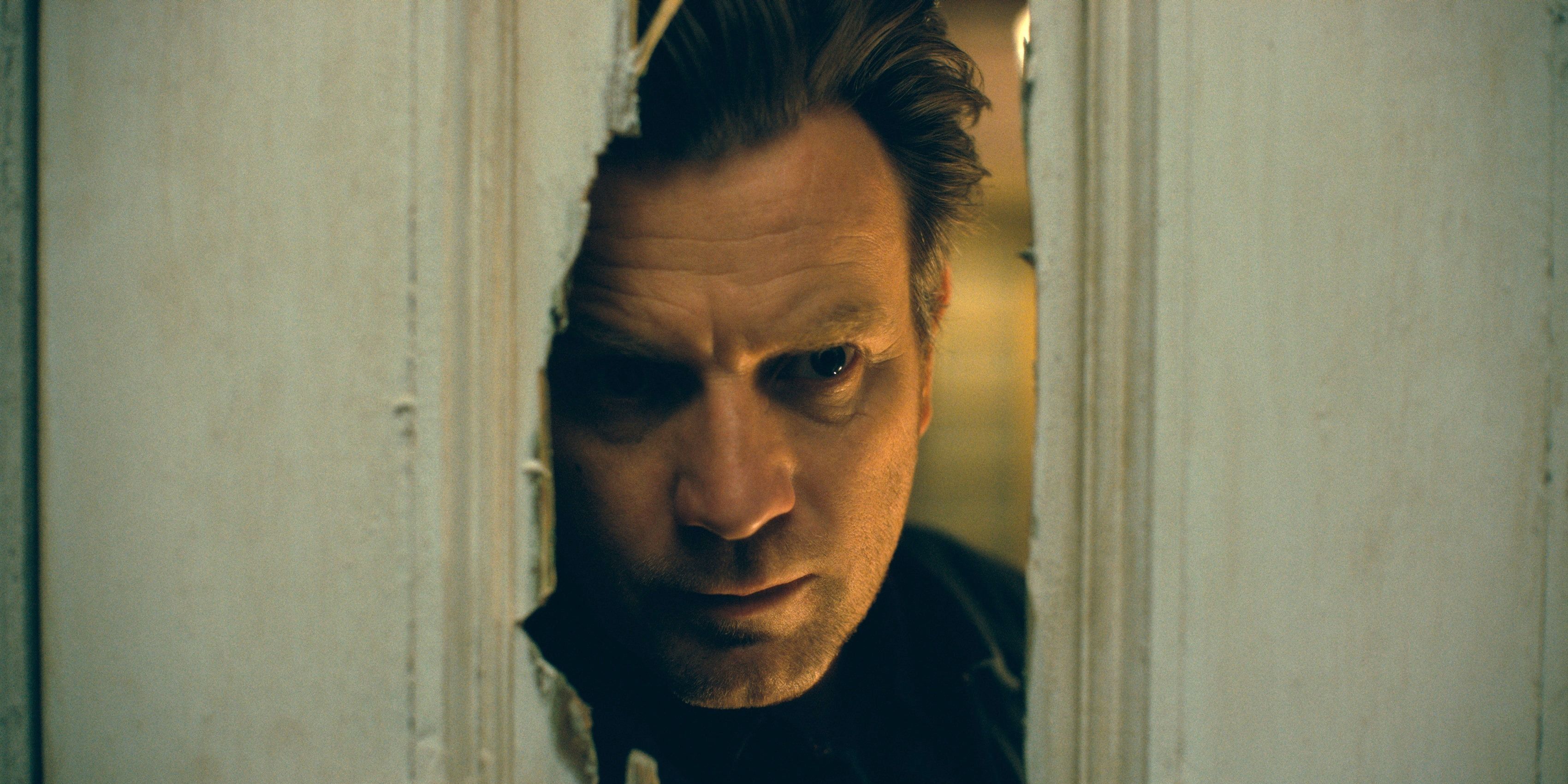 Ewan McGregor looking through a broken bathroom door in Doctor Sleep