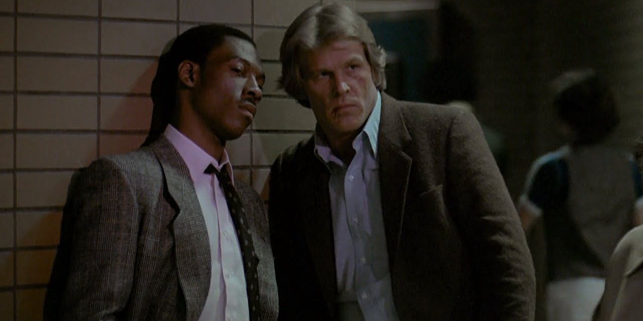 Nick Nolte and Eddie Murphy standing against a wall looking suspicious in 48 Hrs