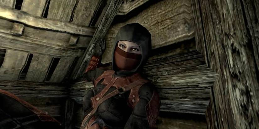 Astrid from the Dark Brotherhood sitting in a log cabin in The Elder Scrolls V: Skyrim