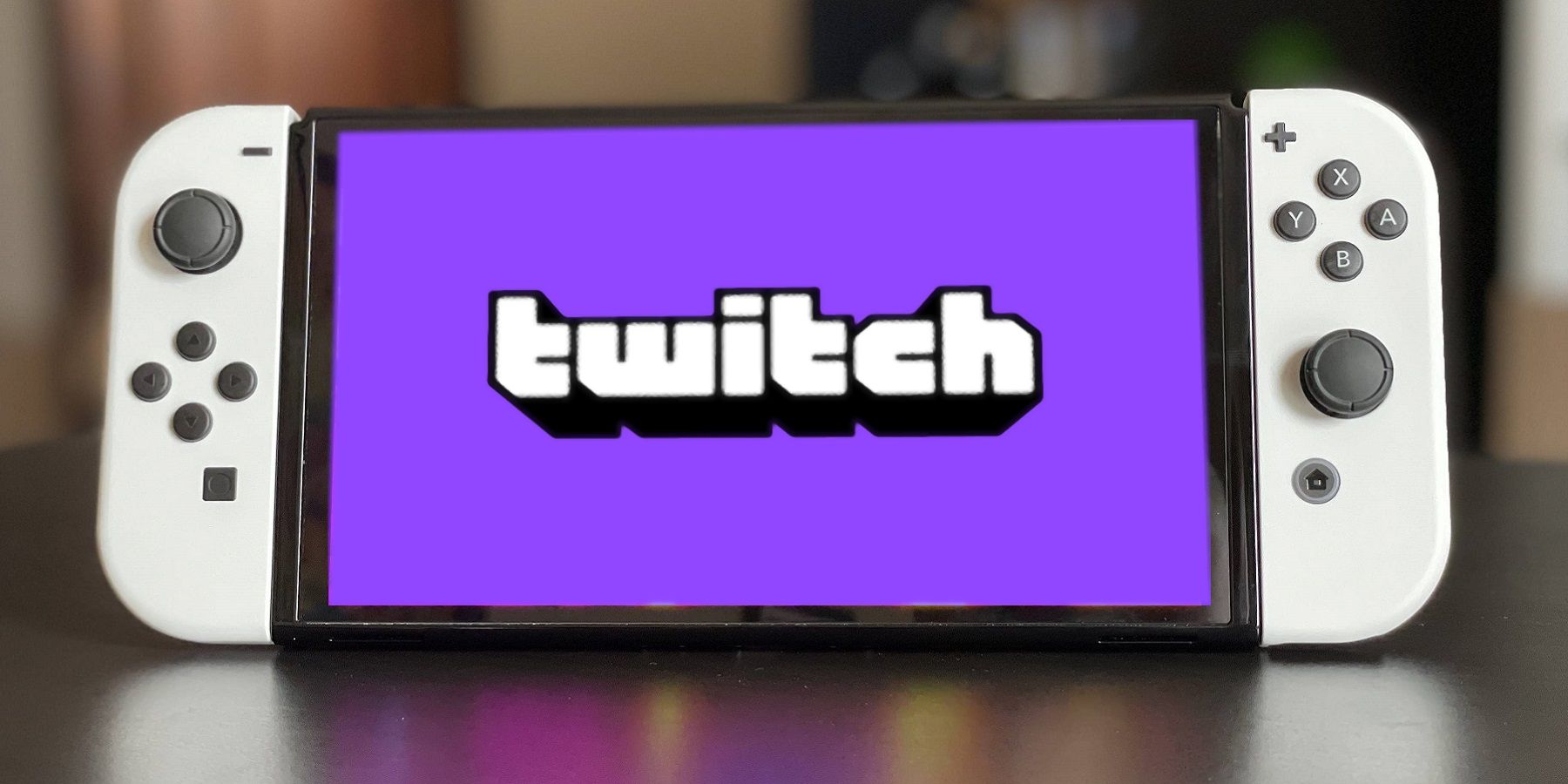 A photo of a white Nintendo Switch with the Twitch logo on the screen.