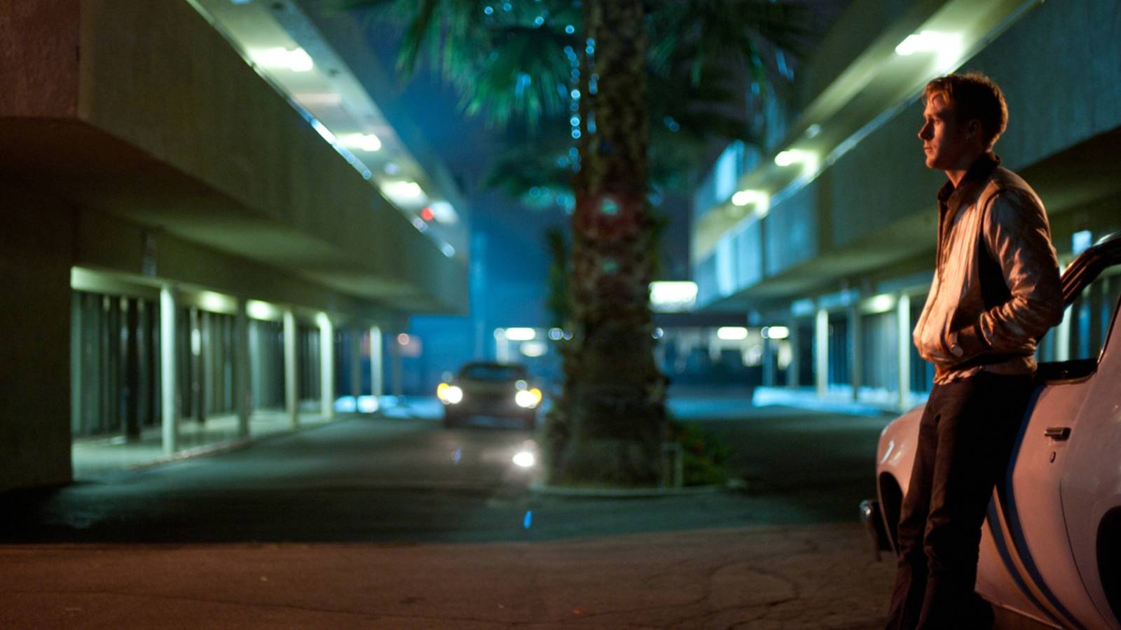 ryan gosling leaning against a car in drive