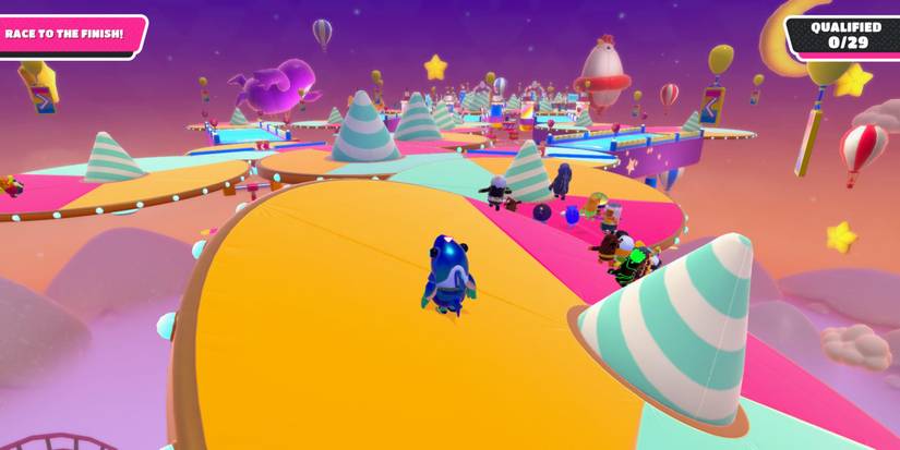 a fall guy bean in a shark costume standing on a tilting platform with the whole course in the distance